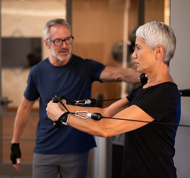 A person helping another with weights.