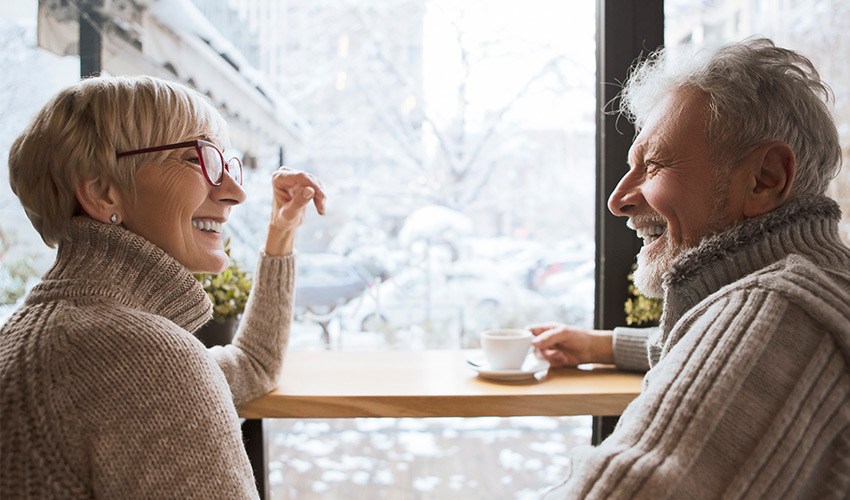 two friends having a cup of coffee by a snowy window