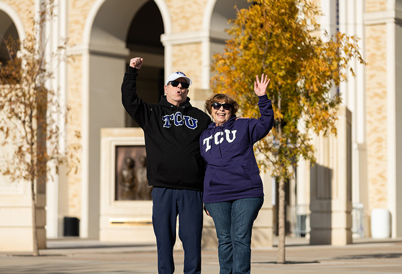 Couple cheering with TCU sweatshirts on.