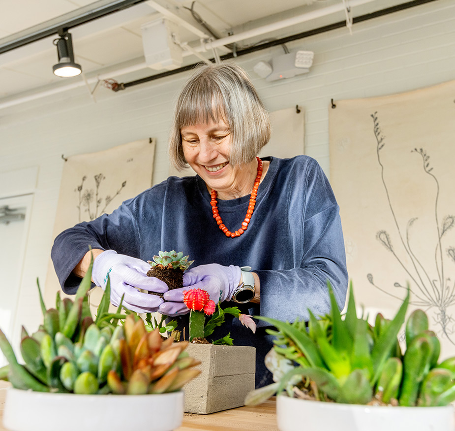 A resident tending to some plants in the greenhouse.