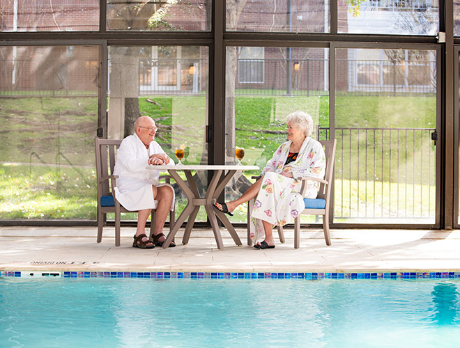 Senior couple sitting at the pool with iced tea.