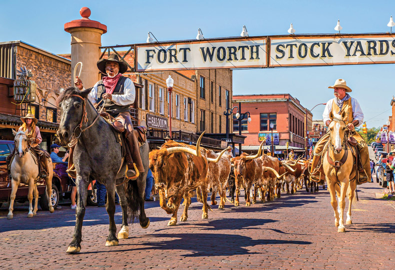 Cowboys on horses coming down a street.