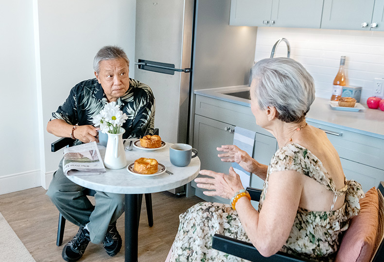 Two residents are eating in their apartment.