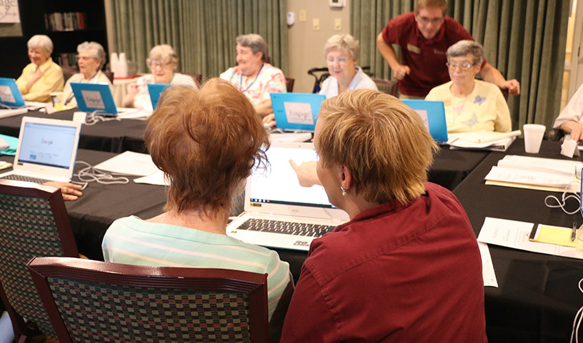 A room filled with seniors on computers for a seminar.