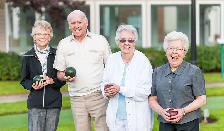 A group of seniors smiling holding bocce balls.