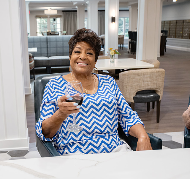 A resident sitting at a table holding a glass of red wine