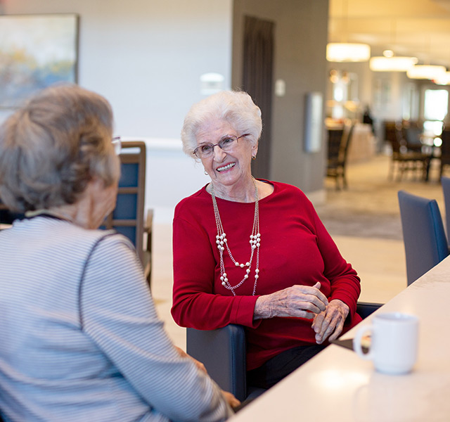 Residents sitting in dining room enjoying coffee.