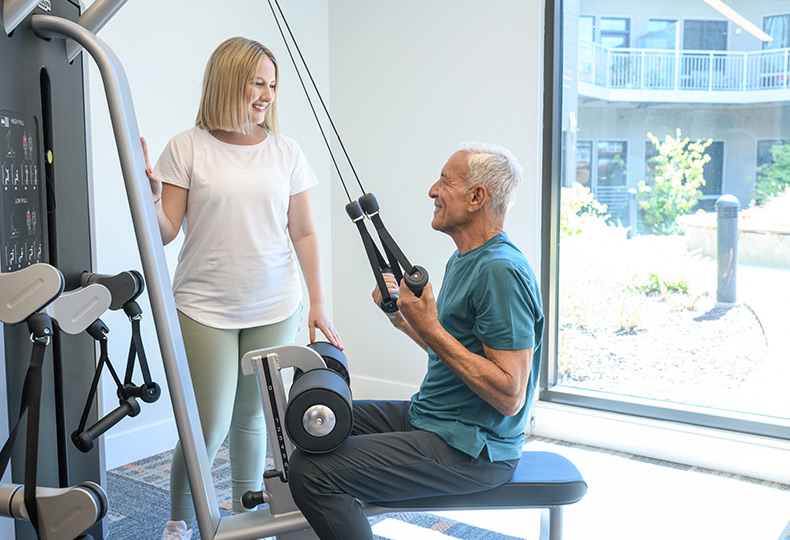 A resident is using a machine in the fitness center.