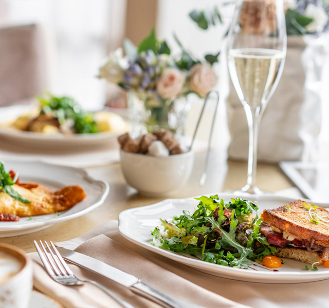 Bright, sunny table set with fine china, silverware and cloth napkins each plate holding a delicious and healthy entree.