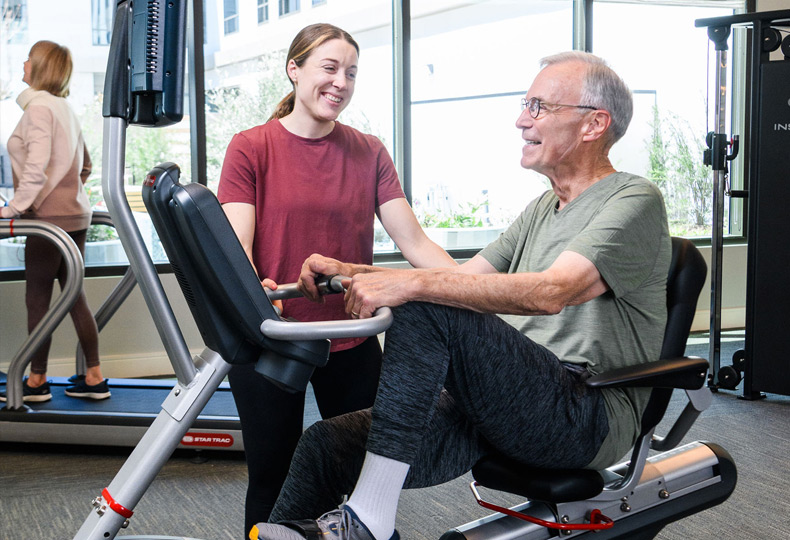 An associate helps a resident use a fitness machine.