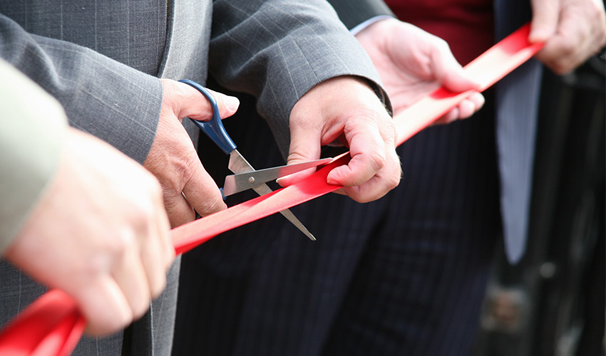 people cutting a red ribbon