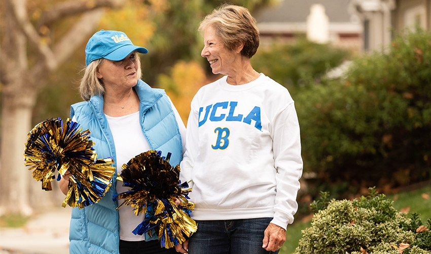two friends smiling and talking wearing UCLA spirit wear
