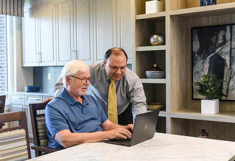 A resident is on the computer getting help from another person.