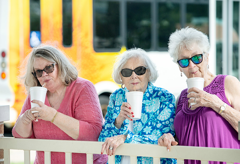 Residents wearing sunglasses standing outside sipping out of straws