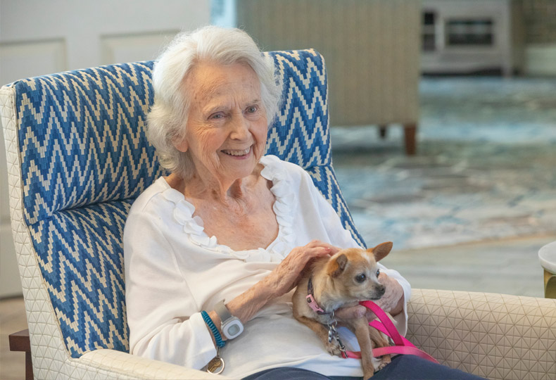 A resident sitting in chair with small dog