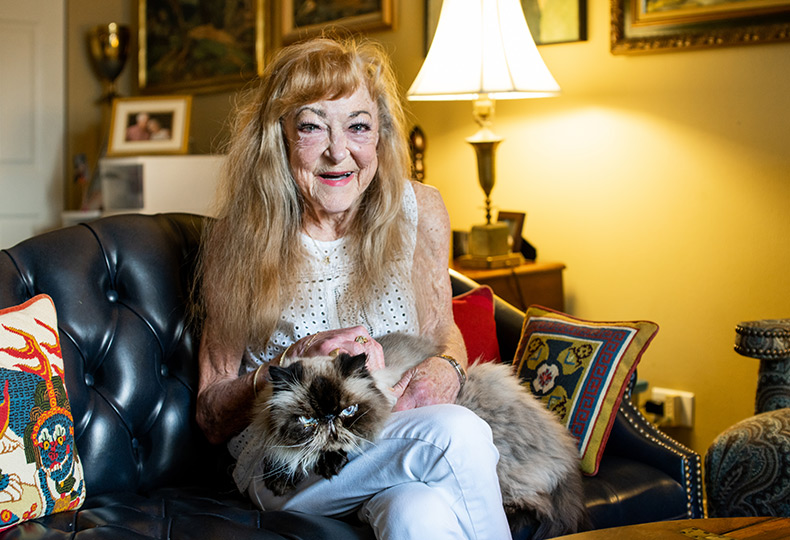 smiling resident sitting on sofa and holding a cat