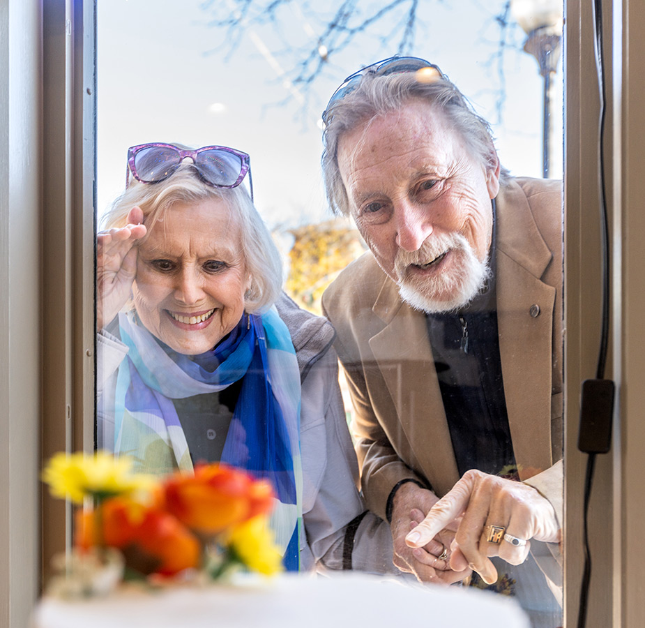 Two residents are looking through a window.