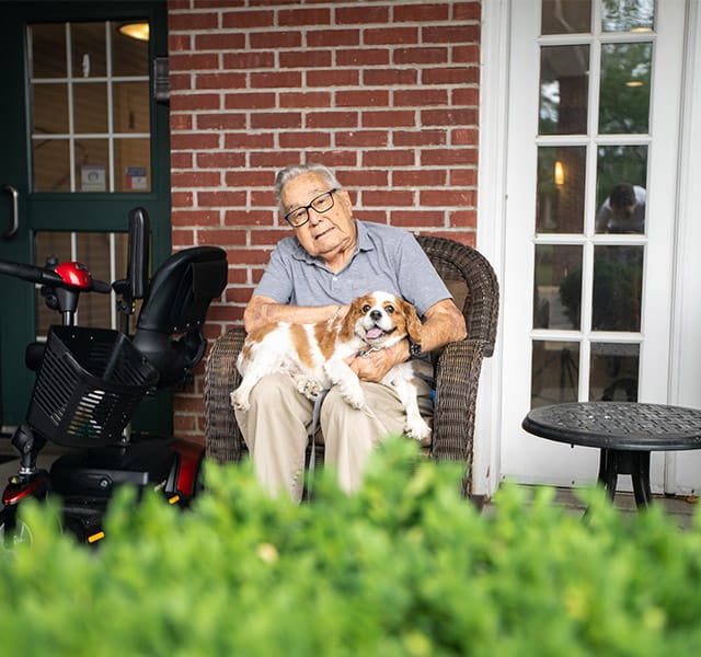 Resident sitting down on a chair with their dog.