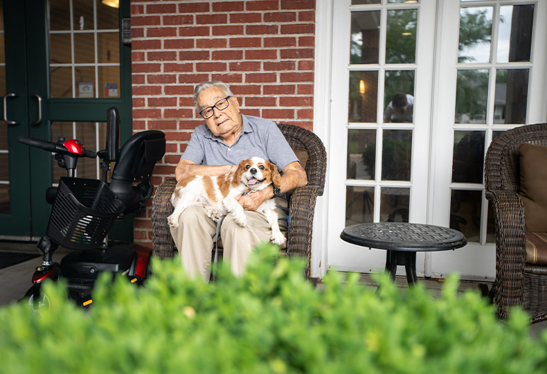 Resident sitting down on a chair with their dog.