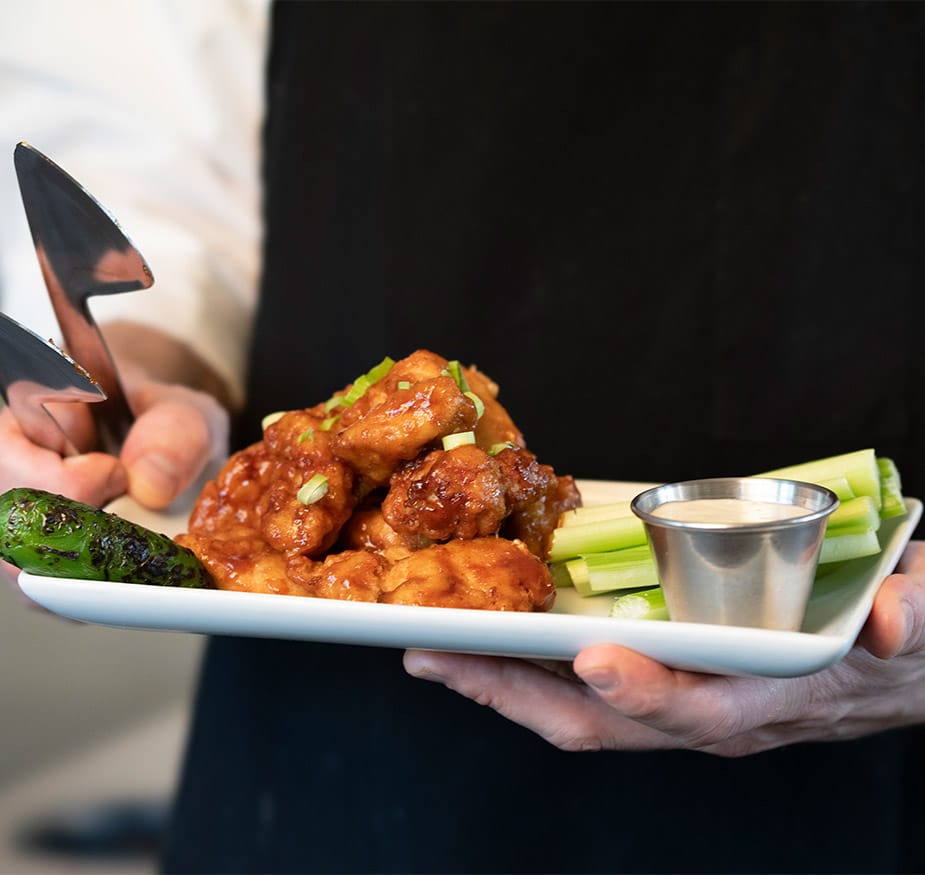 Chef with plate of buffalo wings.