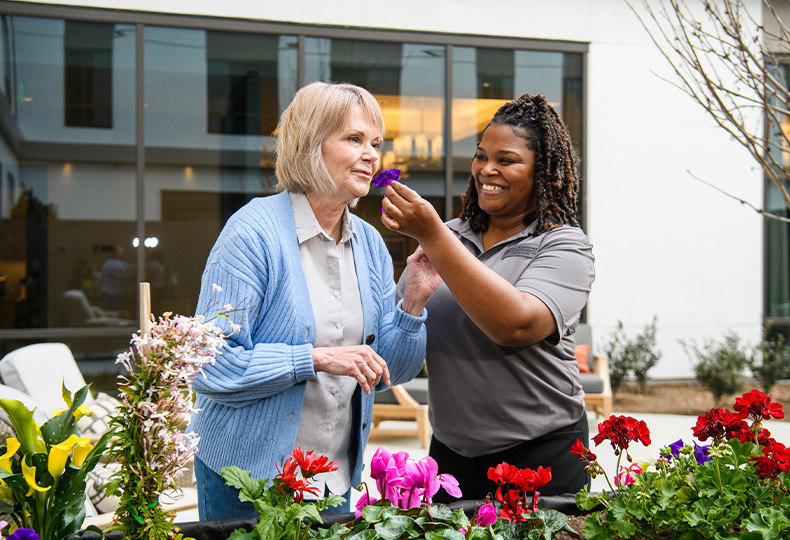 A resident gardening and smelling flowers.