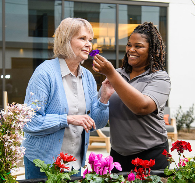 A resident gardening and smelling flowers.