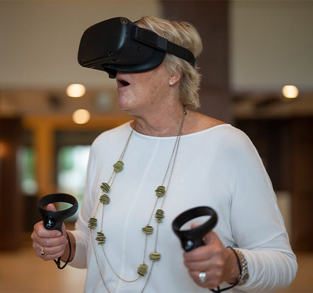 Residents enjoying virtual reality wearing goggles and holding controls.