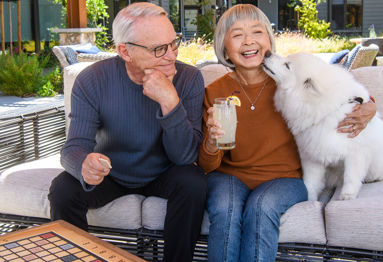 Residents laughing while sitting at the patio with their dog.