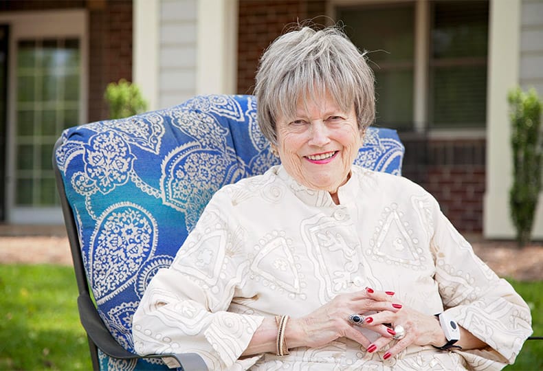 A resident sitting on a chair and smiling for the camera.