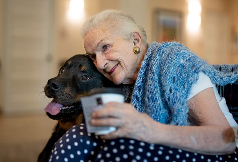 A resident hugging a black lab
