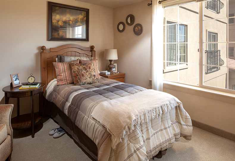 Furnished bedroom featuring a bed, side table, and window.