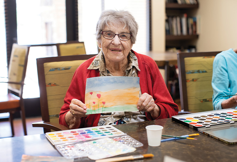 Residents enjoying an art class with canvases and paint brushes.