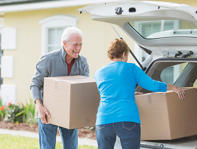 Two people are putting boxes in a car.