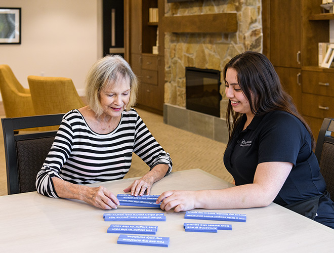 A caregiver is working with a resident on a letters game.