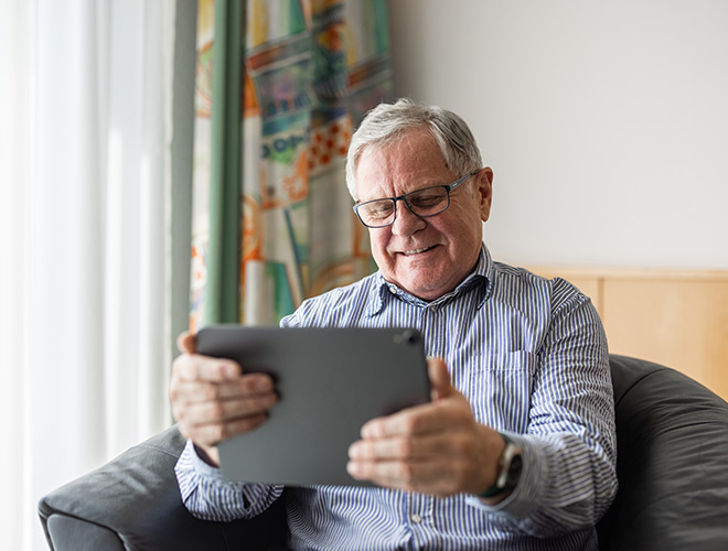 A senior man on his iPad in his living room.