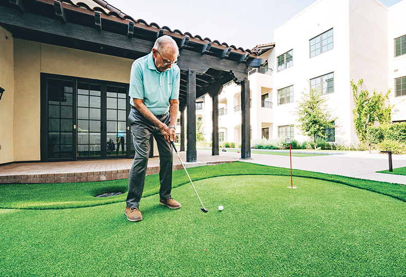 A resident is putting on a putting green.