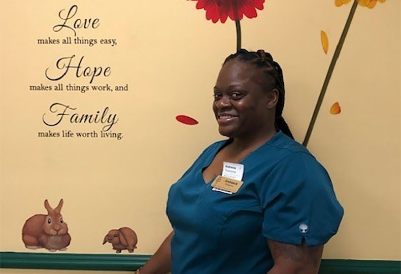 Andresia, a Watermark associate, smiling in front of a painted wall.