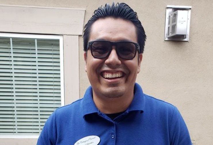 Miguel, a Watermark associate, is smiling outside wearing sunglasses.