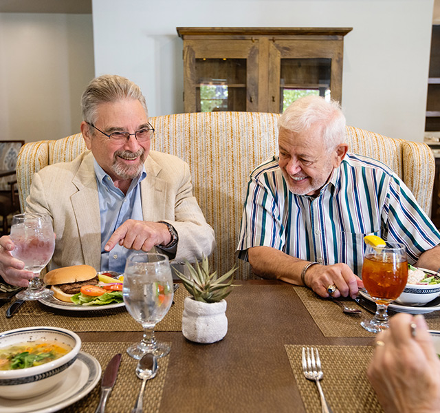 two residents sitting at a table laughing and enjoying their lunch with two other residents