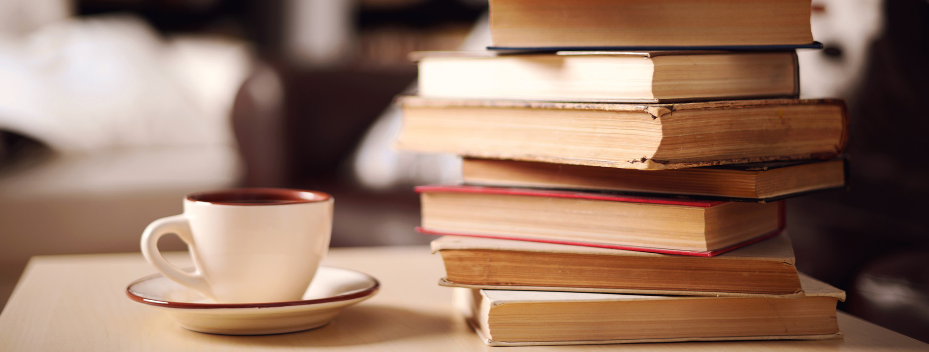 A stack of books with a cup of coffee.