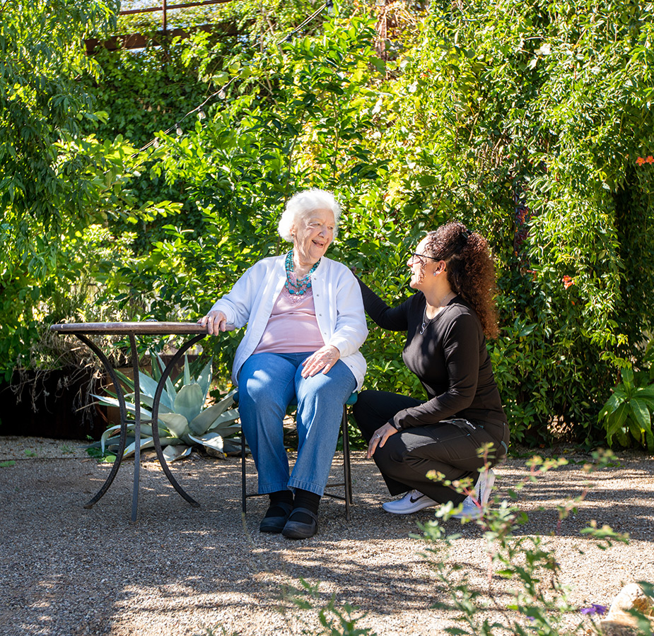 A resident is chatting with their caregiver outside.