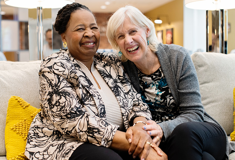 Two friends sitting on the couch laughing.