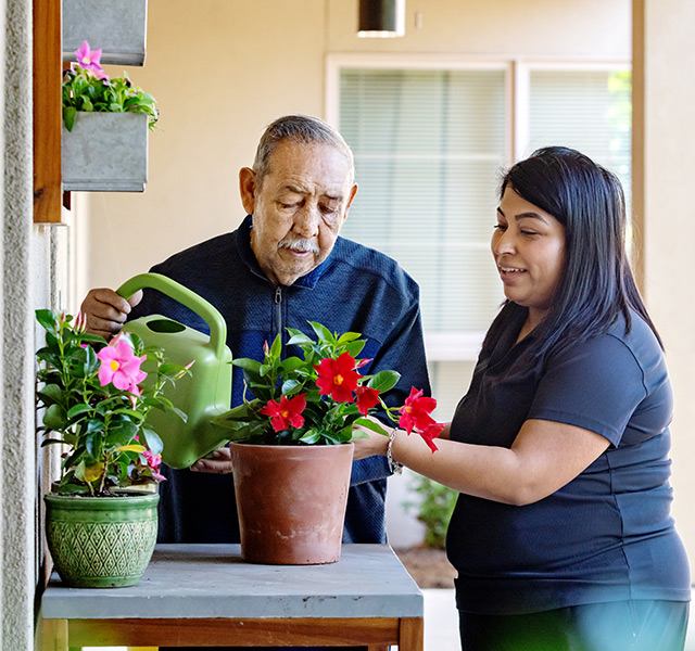 A naya caregiver helping a resident in the garden.