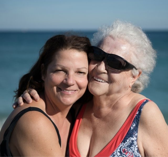 Two women are hugging at a beach.