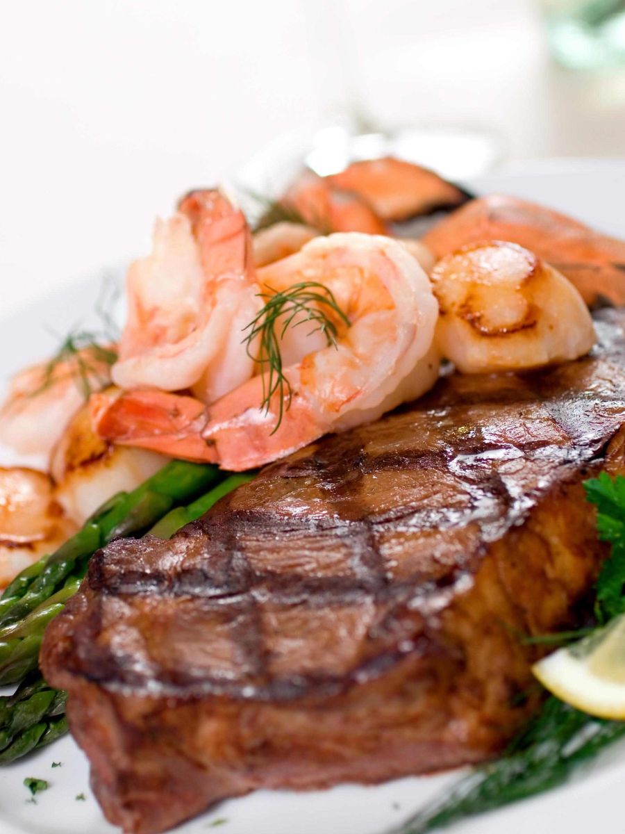Steak topped with shrimp and a side of asparagus.