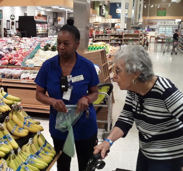 Janet-Associate-shopping Resident and associate choosing bananas at grocery store.