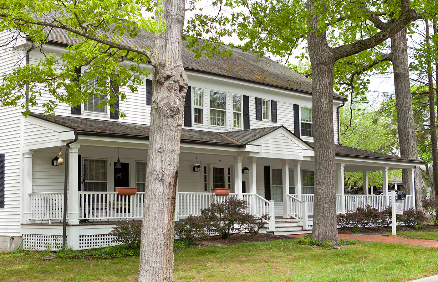 A large white house with a wrap around porch.