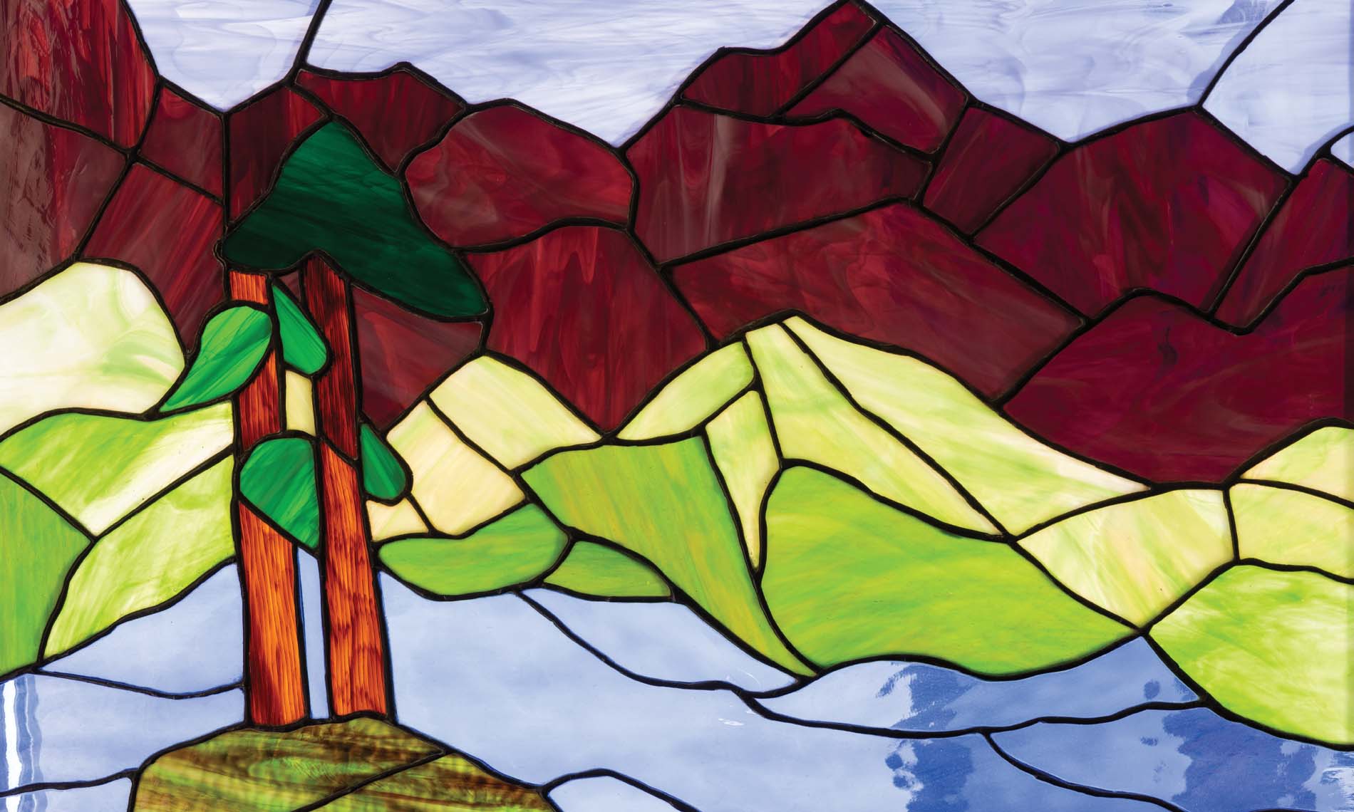 9September A piece of stained glass art of mountains, fields, and trees.