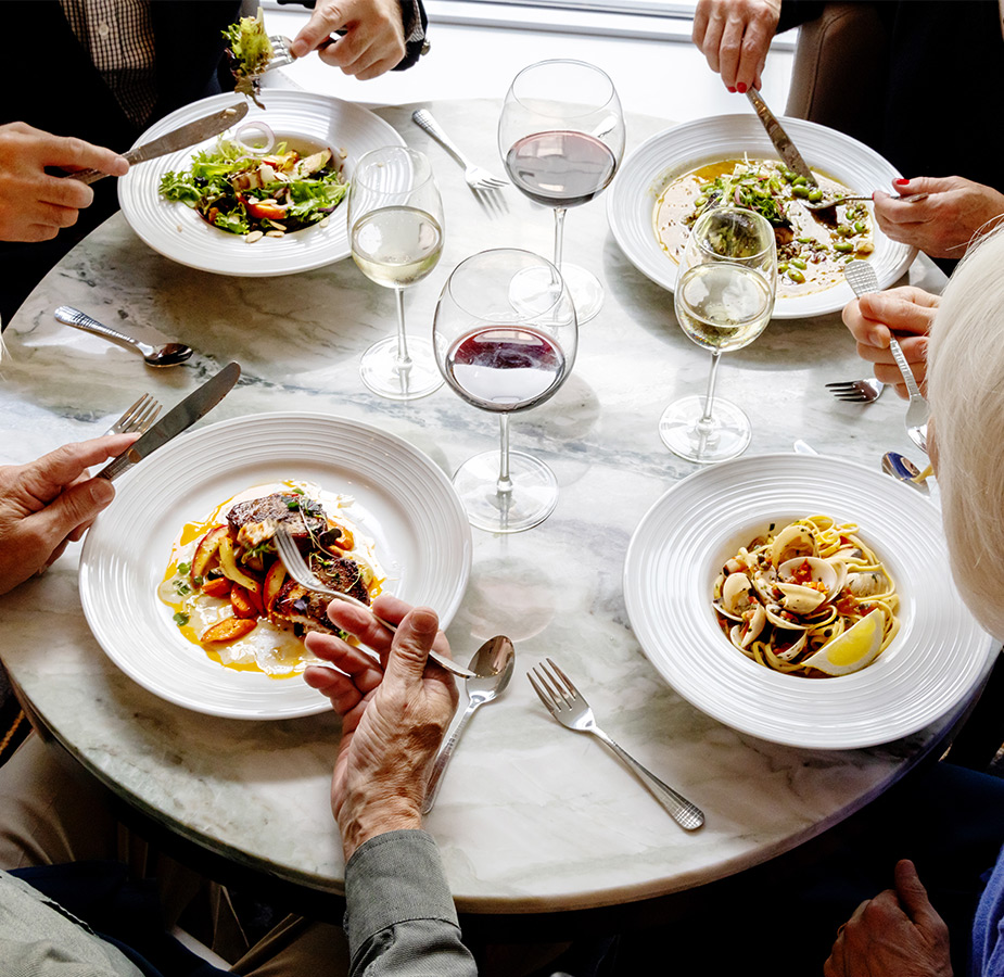 A table with plates full of food being eaten.