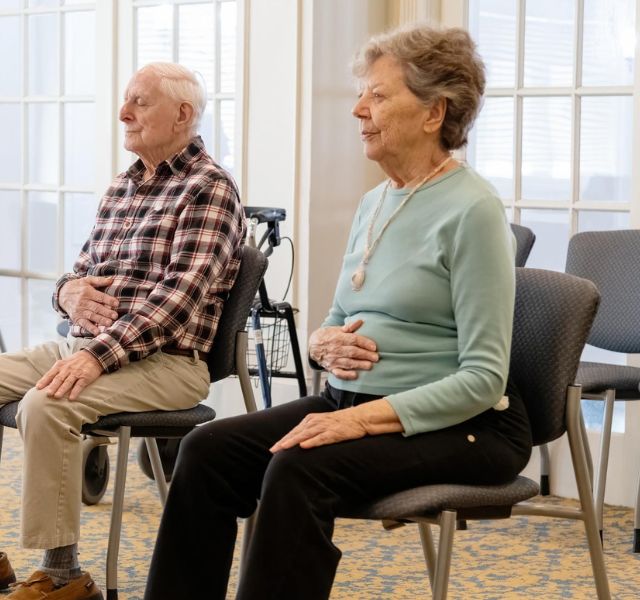 Breath Two residents sitting in chairs with hands on their stomachs.